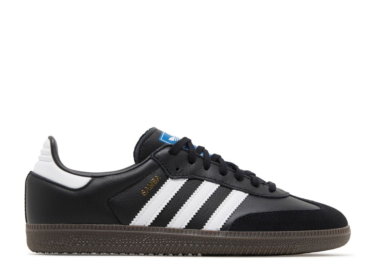 The Adidas Samba OG Black White Gum GS features black uppers, white stripes, a white heel detail, brown gum sole, "SAMBA" in gold on the side, and a blue Adidas logo on the tongue.